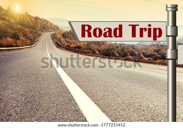 Plaque with inscription road trip on asphalt\
highway at sunset