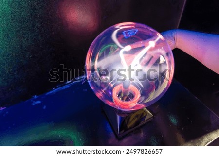 Plasma globe on dark background with vibrant pink and purple electric arcs, science, electricity, physics demonstration, educational toy, interactive plasma ball, high voltage, Tesla coil sphere power