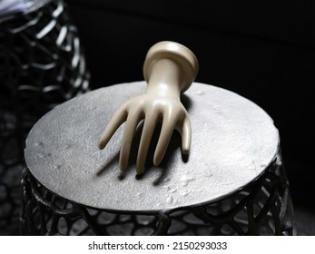 Plaster Hand Lying On A Round Dark Table. Gentle Gesture.