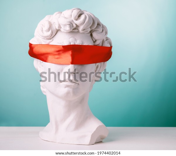 Plaster head with eyes covered red\
satin ribbon on blue background. Avoid problems\
concept.