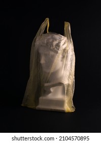 Plaster Male Head In A Plastic Bag Against Black Background, Minimal Creative Layout, Popular Artwork, Mass Tourism Idea. Modern Global Consumerism Idea.   