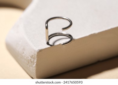 Plaster podium with ear cuff ring on beige background