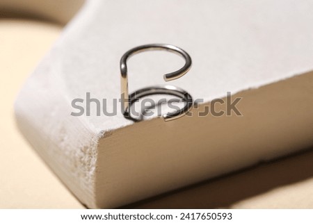 Plaster podium with ear cuff ring on beige background