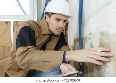 Plasterer Inspecting The Wall