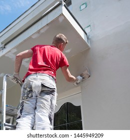 Plasterer In Red Shirt Works On White Plaster Of Old House During Insulation Work