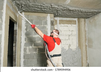 Plasterer Using Sprayer Machine Putting Plaster Mortar On Ceiling