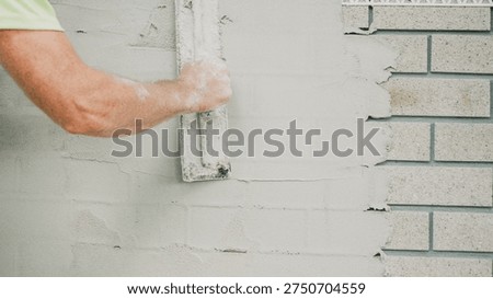 Plastering Rendering Construction Wall Renovation Masonry Handyman applying fresh white plaster coat on a brick wall with a professional trowel tool during home improvement.