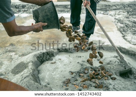 Plastering work on the floor outside the house By an elderly person mixing cement by using gravel stones, sand, cement,water and using a shovel device to mix together.