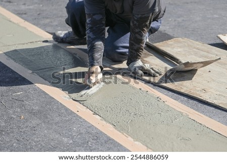 Plastering work. Worker uses a trowel and cement to plaster a floor.
