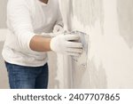Plasterwork and wall painting preparation. Asian male applying plaster or filling drywall patch	
