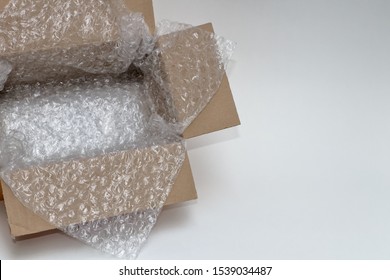 Plastic Air Bubble Wrapped Items In Open Brown Cardboard Box, Ready To Be Shipped.