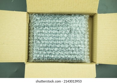 Plastic Air Bubble Wrapped Items In A Brown Cardboard Box, Ready To Be Shipped.