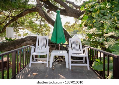 Plastic Armchair With Table And Parasol On Patio In The Garden