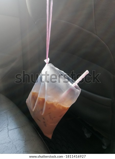 A plastic bag filled with Ice Tea drink, hanging\
in the car. Tied by Raffia rope.\
Image may contain noise or grain\
due to low light.