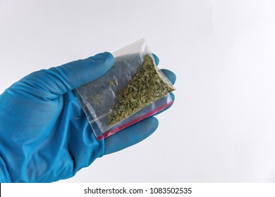 Plastic Bag Of Synthetic Smoking Substances In Hand: Cannabis, Weed, Marijuana. On White, Top View