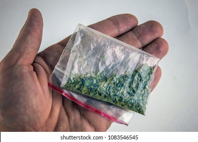 A Plastic Bag Of Synthetic Smoking Substances In The Hand Of A Smoker: Cannabis, Weed, Marijuana. On White, Top View