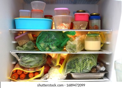 Plastic Bags And Container With Frozen Food And Vegetables In Refrigerator Background.