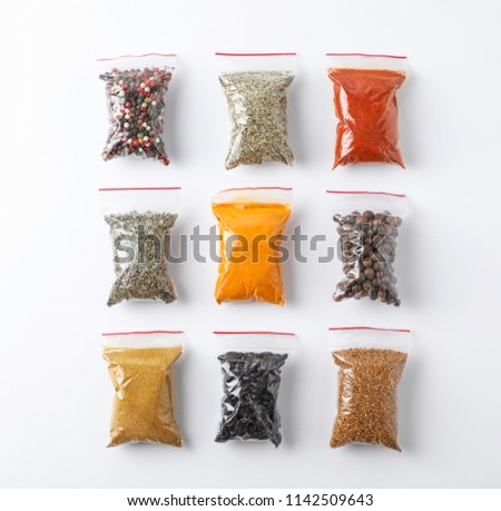 Plastic bags with different spices on white background, top view