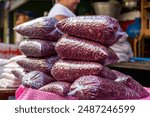 Plastic bags full of uncooked red kidney beans, piled up on a table in an outdoors market in El Salvador. Packaged bags of adzuki beans, ready for cooking.