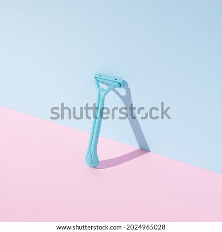 Plastic beard razor with shadow on pastel pink and blue background.  Razor for men's and women shaving. The art of body purity. Front view.