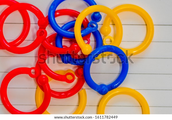 Plastic binder rings in yellow,blue and red\
laying on top of blank white index\
card.