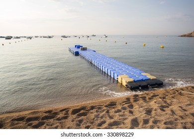 Plastic Blue Rotomolding Jetty In The Empty Sea Against Blue Sky.