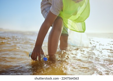 Plastic bottle, cleaning ocean and kid with environment and climate change, environmental and volunteer for Earth day. Water pollution, nature and children clean up beach for eco friendly activism - Powered by Shutterstock