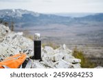 A plastic bottle filled with liquid is placed on a rocky mountain, overlooking the breathtaking skyline. A perfect spot for recreation and enjoying the mountain landscape