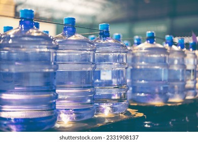 Plastic bottle or gallon of purified drinking water inside drinking water or beverage factory which has automated conveyor production line. Water manufacture, toned