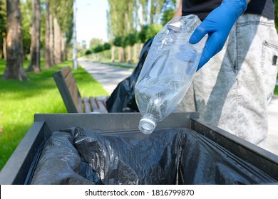 A Plastic Bottle In The Hand Of A Volunteer Picking Up Rubbish In A Public Park And Throwing The Bottle Into The Trash Can. Environmental Protection Conce.