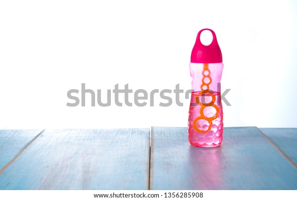 Plastic bottle of soap\
bubbles on wood