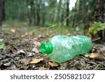 Plastic bottle thrown away in forest. Garbage in nature, reusable products. Rubbish thrown in forest. PET Plastic water bottle thrown out in nature. Waste in nature. Abandoned pet garbage waste.