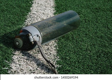 plastic bottle of water lying on grass soccer field.