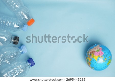 Plastic bottles arranged facing a small globe, symbolizing global pollution and environmental threat caused by plastic waste.