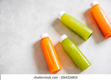 Plastic bottles of cold-pressed unprocessed fruit and vegetable juices, from above, light gray table. Body cleance, fast concept. Minimalism food photography