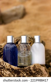 Plastic Bottles With Natural Cosmetic In Travel Containers - Blue Shower Gel, Shampoo With Bubbles Inside, Body Lotion In Miniature Containers Against A Brown Stone Rock Background. Face Body Care. 