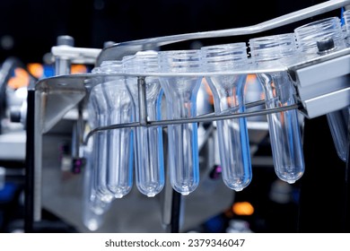 Plastic bottles in production line at manufacturing. PET perform in PET bottles blowing in blowing machine at drink water factory.  - Powered by Shutterstock