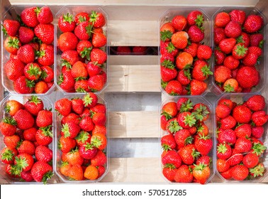 Plastic box package of red fresh strawberries on a wood box, top view
