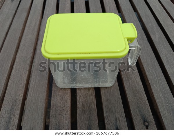 A
plastic box for spices lies on wooden brown
plank.