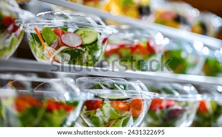 Plastic boxes with pre-packaged fruit and vegetable salads, put up for sale in a commercial refrigerator