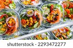 Plastic boxes with pre-packaged vegetable salads, put up for sale in a commercial refrigerator