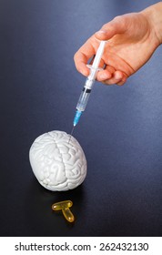 Plastic Brain Injection And Omega 3 Capsules On Isolated Black Background