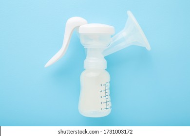 Plastic breast pump bottle on light blue table background. Pastel color. Closeup. Preparing milk for baby feeding.