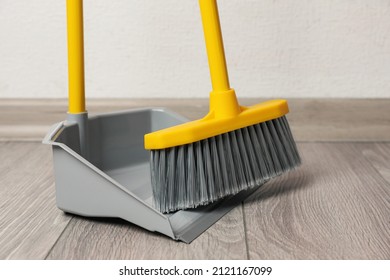 Plastic broom with dustpan on wooden floor indoors - Powered by Shutterstock