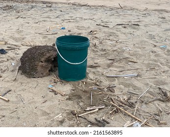 Plastic Bucket With Green Color On The Dirty Beach Sand With Wide Shot