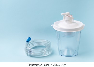 Plastic Canister From Medical Suction Machine On Blue. Part Of Portable Aspirator Used To Remove Mucus, Blood, Bodily Fluids From Patient. Medical Equipment Using In Ambulances And Nursing Homes