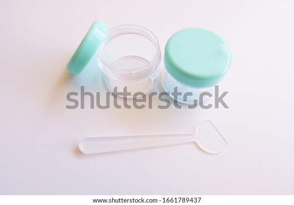 Plastic case for dividing the skin care cream\
into a portable bag while traveling abroad. Pies and small plastic\
cartridges For putting on creams and cosmetics while traveling on\
white background.