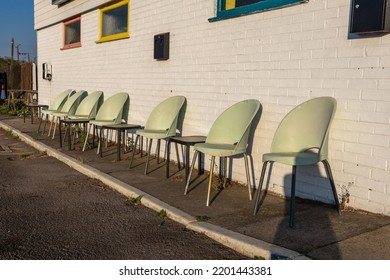 Plastic Chairs Against A Wall. Cheap Cafe Outside Dining Area. Empty Tables And Seats In A Row On The Pavement.