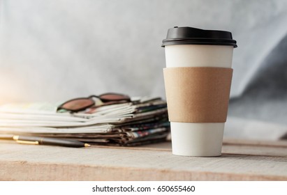 Plastic coffee mugs and newspapers on wooden floor. - Powered by Shutterstock