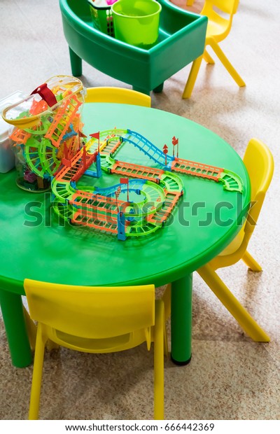Plastic color railway toy\
on green round table at play zone. Creative and fun educational toy\
for kids.